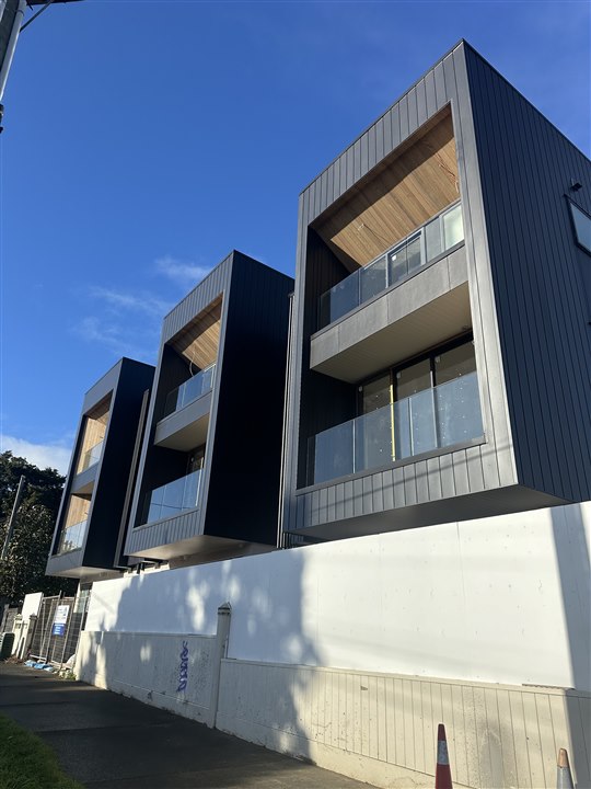 Contemporary townhouses with dark cladding and timber-lined balconies
